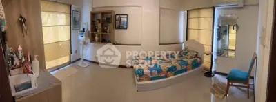 Cozy bedroom with colorful bedding, ample natural light, and modern decor in a stylish apartment.