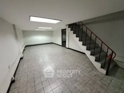 Spacious basement with tiled flooring and staircase, ideal for storage or conversion.
