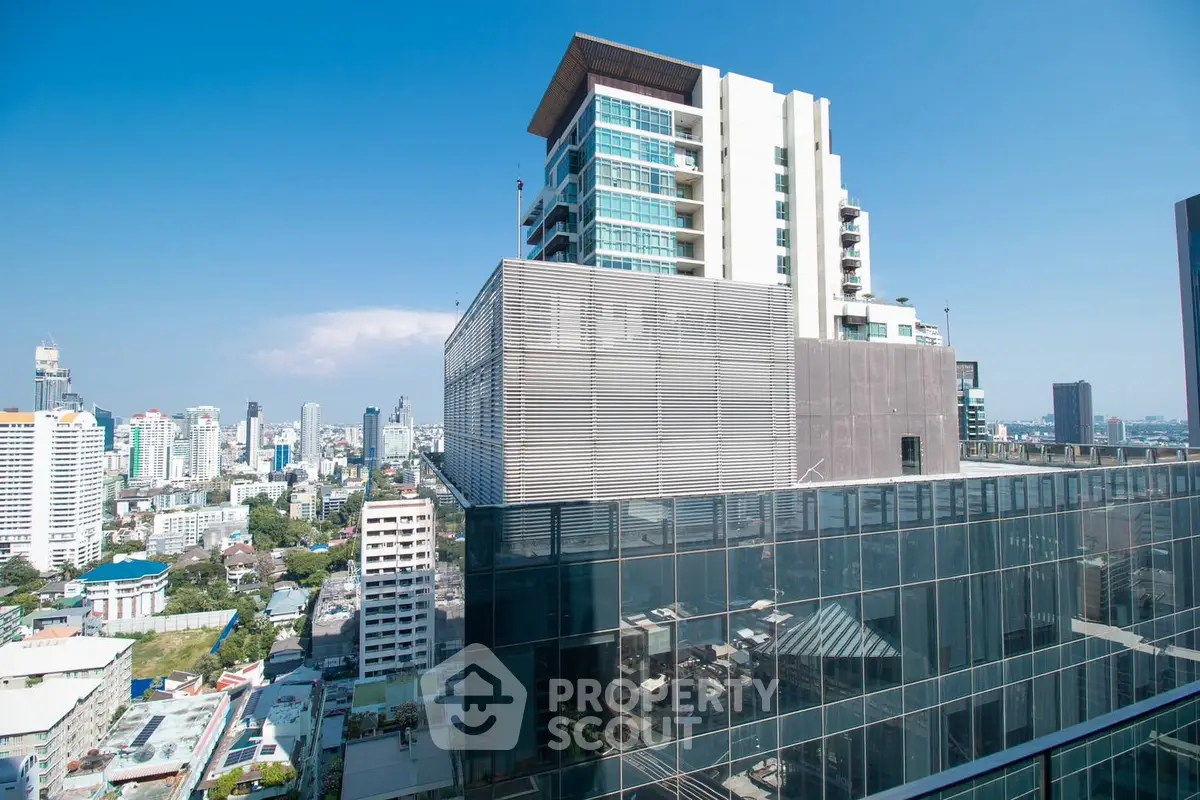 Stunning cityscape view from a modern high-rise building with glass facade and clear blue sky.