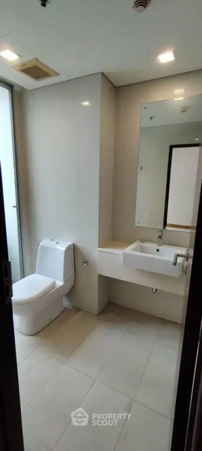 Modern bathroom with sleek fixtures and large mirror in a contemporary apartment.