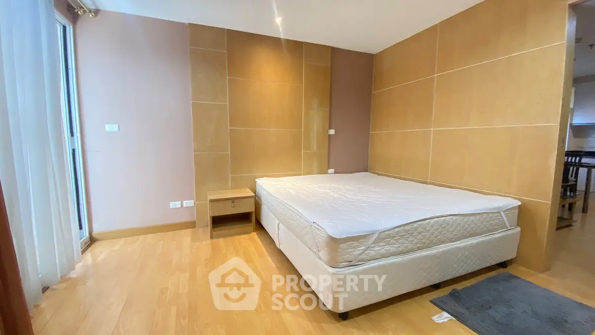 Spacious bedroom with wooden flooring and natural light in modern apartment