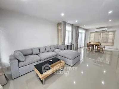 Spacious modern living room with sleek gray sofa and elegant dining area