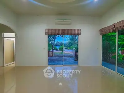 Spacious living room with large windows offering serene garden views