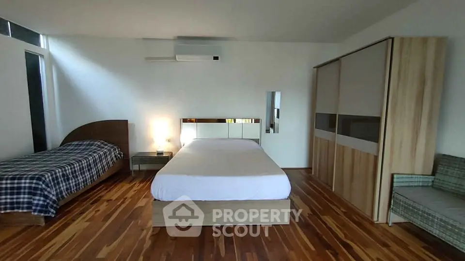 Spacious bedroom with modern wooden flooring and stylish furniture