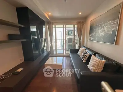 Modern living room with sleek black sofa, wall-mounted TV, and large window offering natural light.
