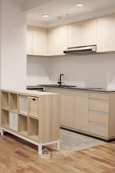 Modern kitchen with sleek cabinetry and open layout, featuring a stylish partition and hardwood flooring.