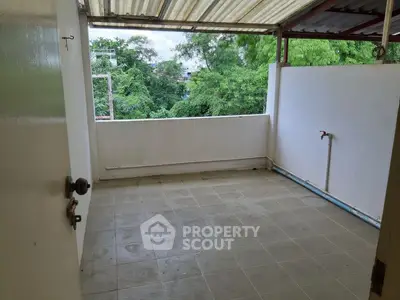 Spacious balcony with tiled flooring and lush green view, perfect for relaxation.