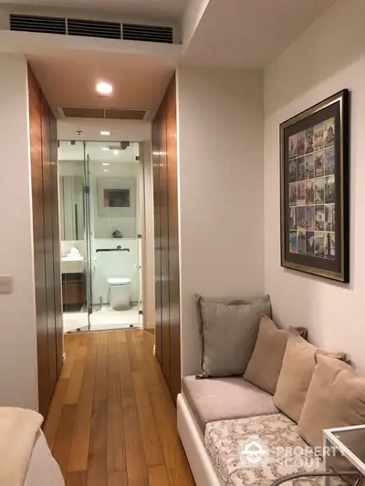 Cozy hallway with seating area leading to modern bathroom