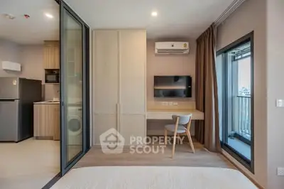 Modern studio apartment with balcony, featuring compact kitchen and stylish workspace.
