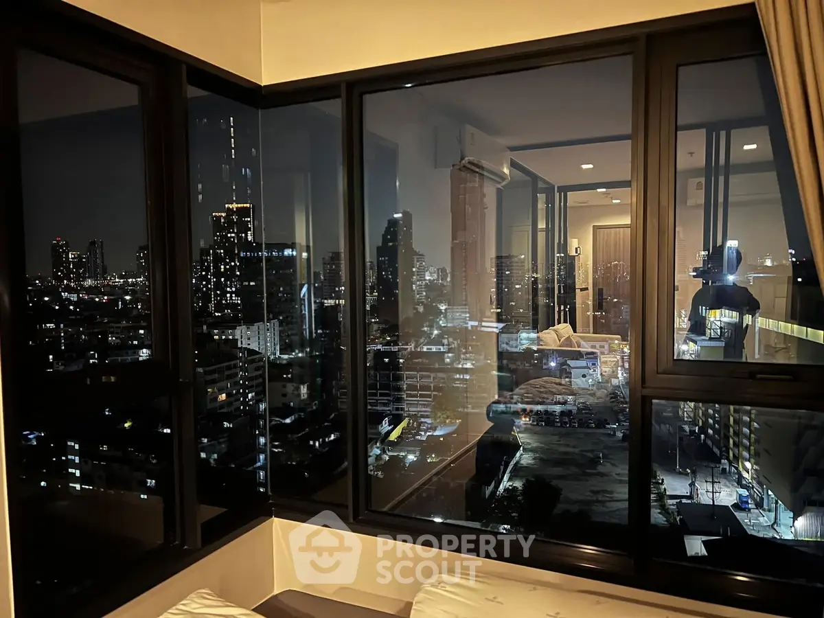 Stunning cityscape view from modern apartment window at night, showcasing urban skyline and cozy interior.