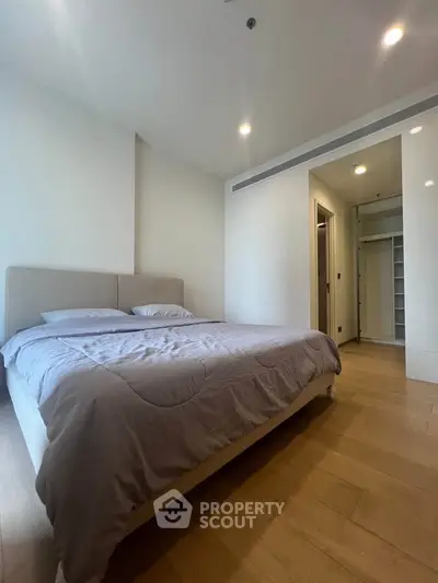 Spacious bedroom with modern design and ample natural light, featuring a comfortable bed and wooden flooring.