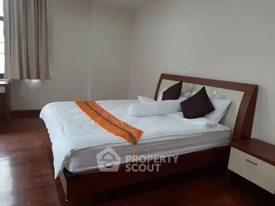 Spacious bedroom with elegant wooden flooring and modern bed setup.