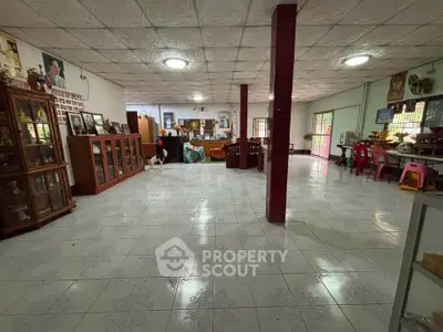 Spacious open-plan living area with tiled flooring and ample natural light.