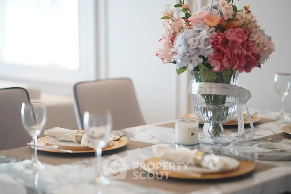 Elegant dining table setup with floral centerpiece and luxurious tableware in a stylish home.