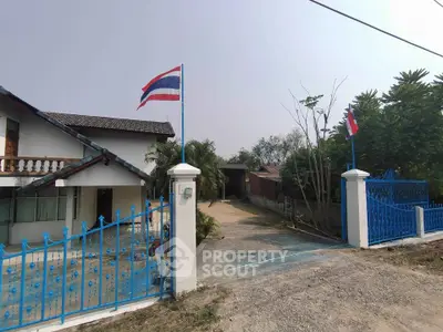 Charming house with blue gate and flags, offering a welcoming entrance and spacious driveway.