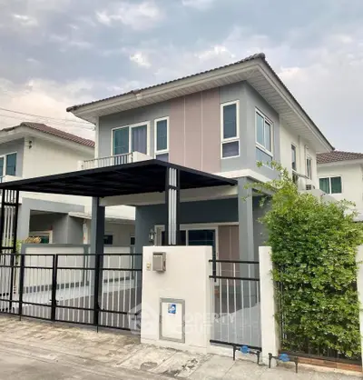 Modern two-story house with sleek design and gated entrance in suburban neighborhood.
