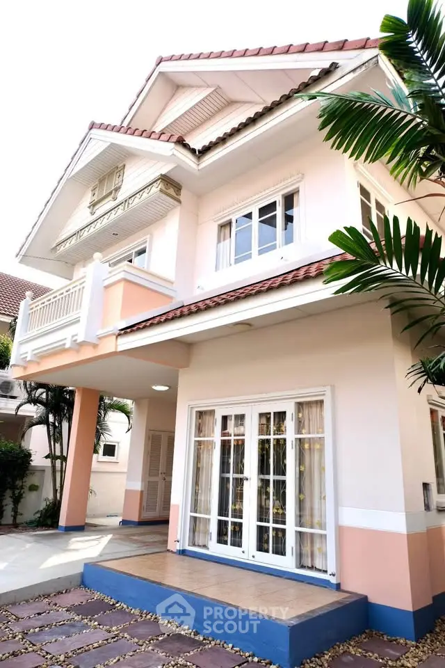 Charming two-story house with elegant balcony and lush greenery, perfect for family living.