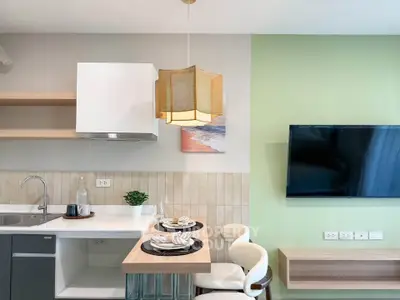 Modern kitchen with stylish dining area and wall-mounted TV in a cozy apartment.