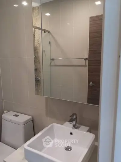 Modern bathroom with sleek fixtures and glass shower enclosure.