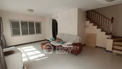 Spacious living room with cozy sofa and staircase, perfect for family gatherings.