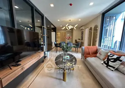 Modern living room with stylish decor and open layout, featuring a large TV and elegant furniture.