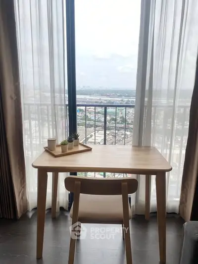 Cozy study nook with a stunning city view from a high-rise apartment balcony.