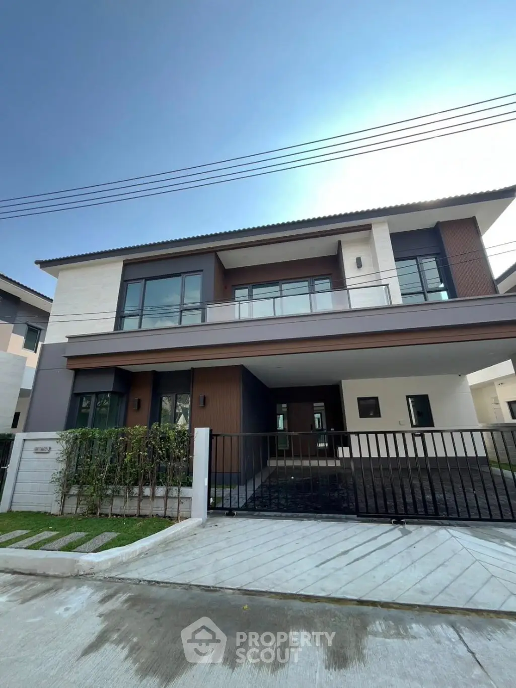 Modern two-story house with sleek design and spacious driveway in a suburban neighborhood.