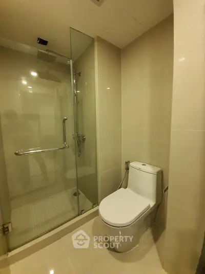 Modern bathroom with glass shower and sleek toilet in contemporary apartment.