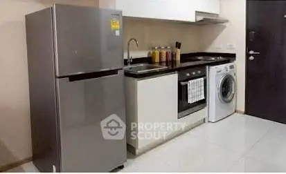 Modern kitchen with sleek appliances including fridge, oven, and washing machine in compact layout.