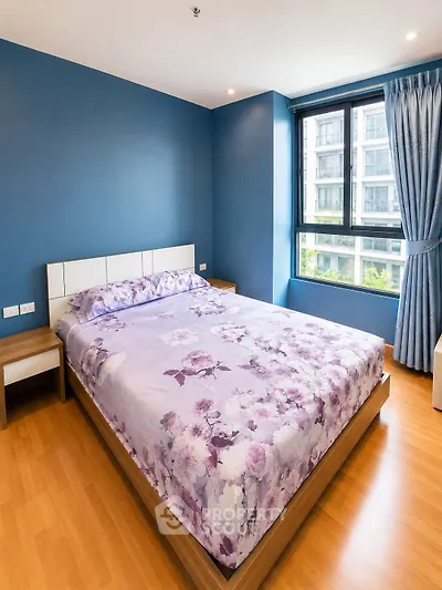 Modern bedroom with blue walls and floral bedding in a high-rise apartment