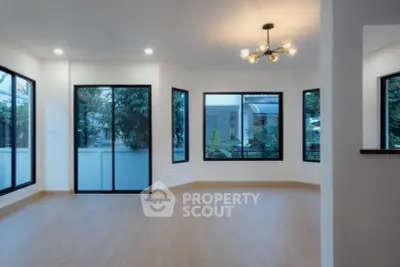 Spacious modern living room with large windows and elegant lighting, offering a bright and airy atmosphere.