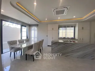 Luxurious modern kitchen with marble island and elegant dining area, featuring sleek design and ample natural light.