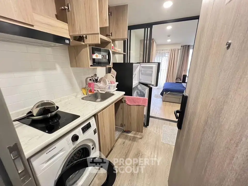 Compact kitchen with modern appliances and open layout leading to cozy bedroom.