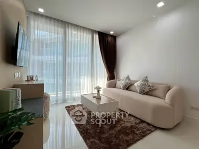 Modern living room with elegant sofa, chic decor, and floor-to-ceiling windows offering natural light.