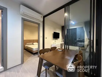 Modern apartment interior with dining area and bedroom view, featuring sleek furniture and ambient lighting.