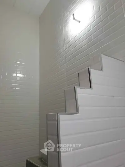 Modern bathroom with sleek white tile design and contemporary lighting.