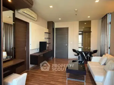 Modern living room with sleek furniture and wooden flooring, featuring a stylish dining area and wall-mounted TV.