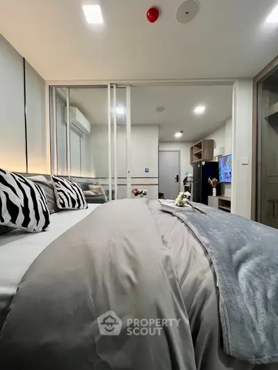 Modern bedroom with stylish decor and sliding glass doors, featuring cozy bedding and ambient lighting.