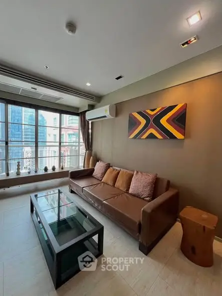 Modern living room with stylish decor and city view, featuring a comfortable sofa and glass coffee table.