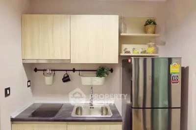 Modern kitchen with sleek cabinetry and stainless steel fridge in compact layout.