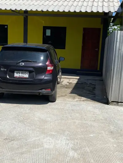 Charming yellow house with a car parked in the driveway, showcasing a welcoming entrance.