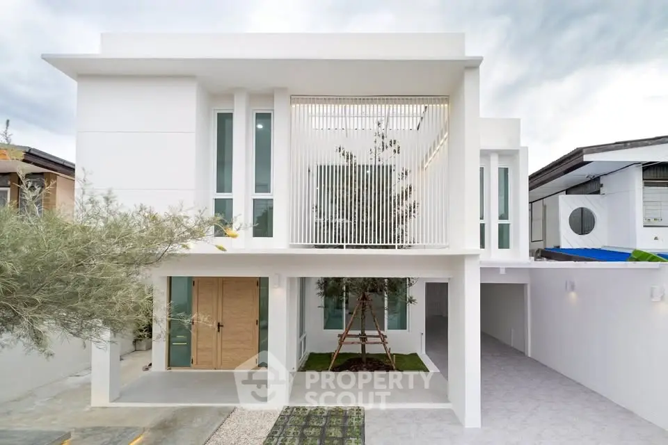 Modern minimalist white two-story house with large windows and clean lines.