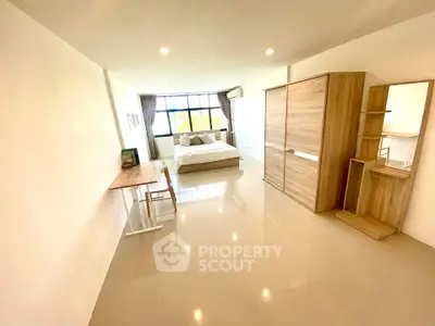 Spacious bedroom with modern furnishings and large window for natural light.