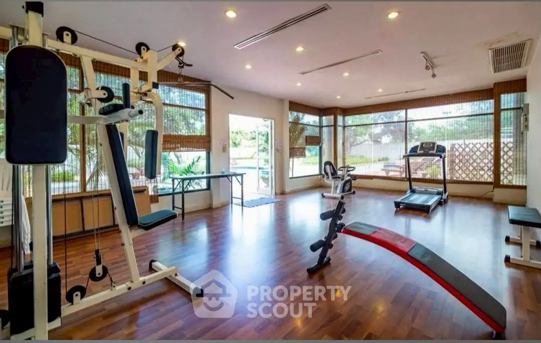 Spacious home gym with modern equipment and large windows for natural light.