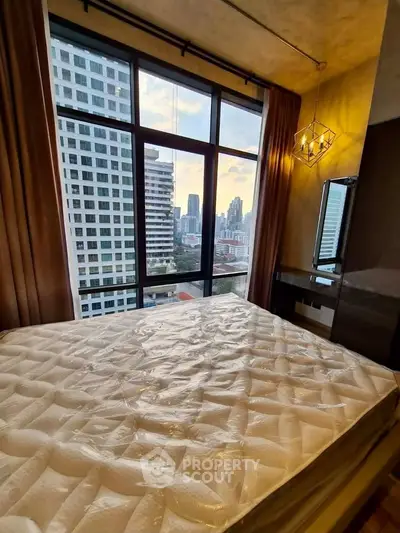 Modern bedroom with large window offering stunning city view in high-rise apartment.