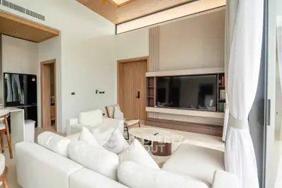 Modern living room with sleek design and large TV, featuring cozy white sofas and wooden accents.