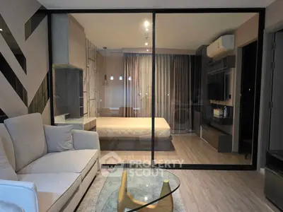 Modern studio apartment with glass partition, cozy living area, and stylish bedroom.