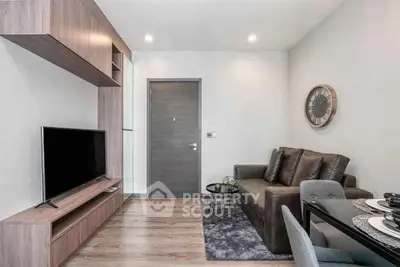 Modern living room with sleek furniture and wall-mounted TV in a cozy apartment.