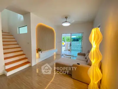 Modern living room with stylish lighting and open layout, featuring a cozy sofa and elegant staircase.