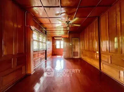 Spacious wooden interior room with ceiling fan and large windows, perfect for cozy living.